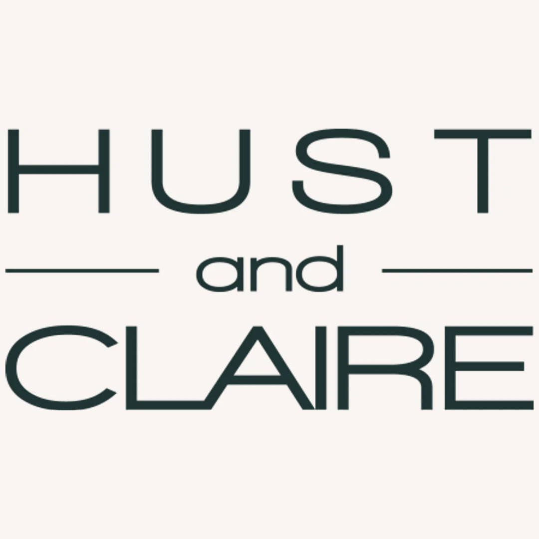 Logo für „Hust and Claire“ mit den Wörtern „HUST“ und „CLAIRE“ in Großbuchstaben und „und“ in Kleinbuchstaben, zwischen horizontalen Linien platziert. Der Text ist in einer dunklen, minimalistischen Schriftart auf hellem Hintergrund gehalten.