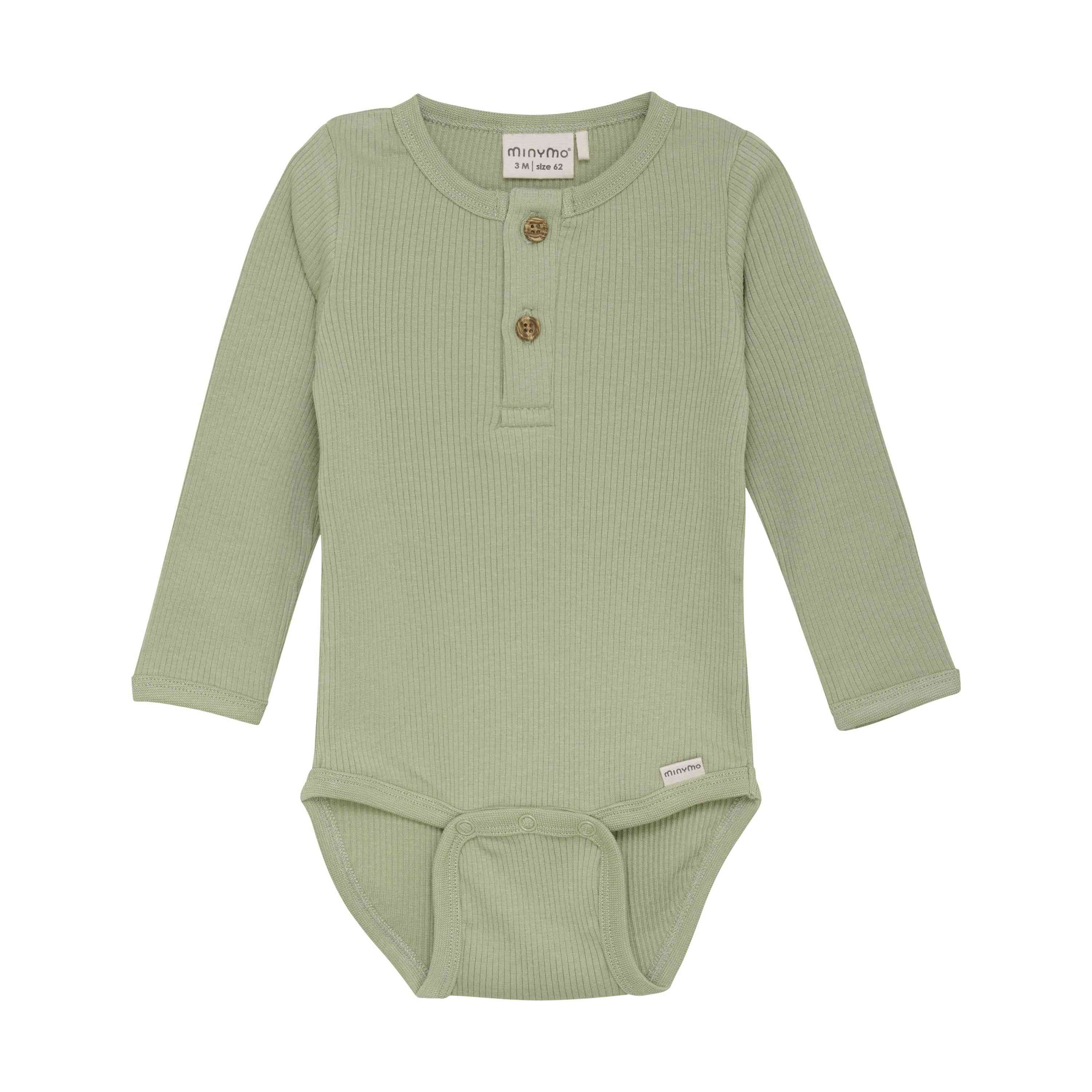Ein Minymo - Body langarm aus Ripp Baby-Strampler, GOTS-zertifiziert für seine Nachhaltigkeit, aus geripptem Stoff mit langen Ärmeln, zwei braunen Knöpfen auf einer kurzen Knopfleiste auf der Brust und Druckknöpfen im Schritt für einfaches Windelwechseln. In die linke Seitennaht ist ein kleines weißes Etikett mit Text eingenäht.