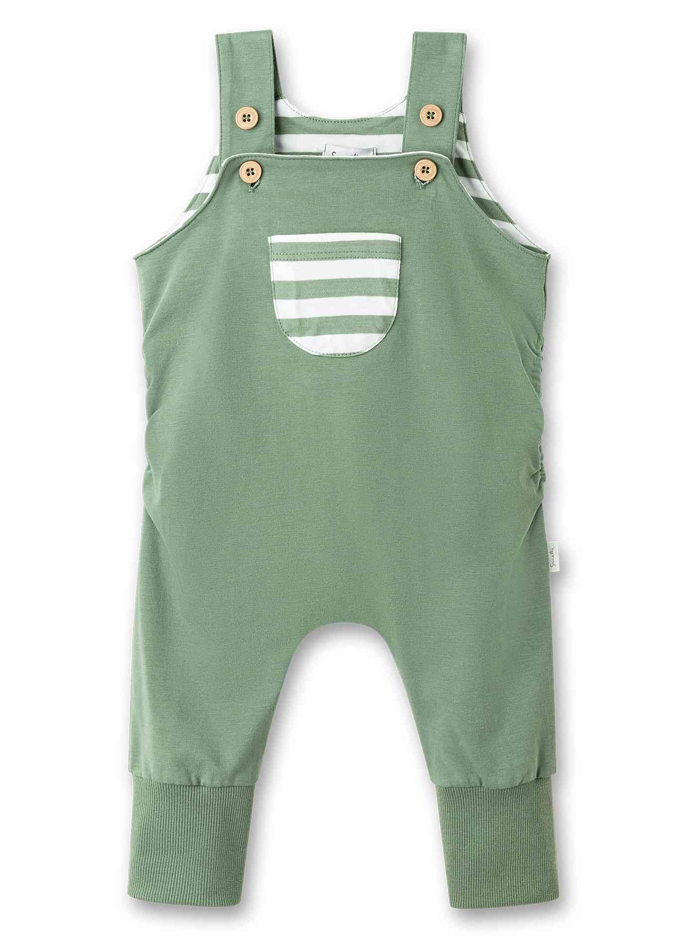 Ein Sanetta - Strampler/Overall mit dicken Schulterträgern mit Knopfverschluss und aus GOTS-zertifizierten Materialien. Der Sanetta - Strampler/Overall hat eine kleine Tasche auf der Brust mit grün-weißen Streifen, Rippbündchen an den Knöcheln und ist zum Mitwachsen konzipiert. Darunter ist teilweise ein weiß-grün gestreiftes Hemd sichtbar.