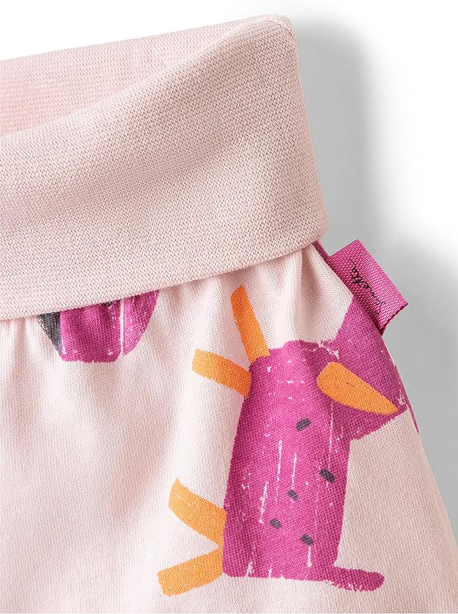 Nahaufnahme eines hellrosa Kleidungsstücks, das als Sanetta-Hose der Marke Sanetta identifiziert wurde. Der Stoff aus Bio-Baumwolle zeigt ein verspieltes Muster mit abstrakten Formen in Rosa und Orange. Auf der Naht ist ein kleines rosa Etikett mit Text zu sehen, das für hochwertige Kindermode steht.