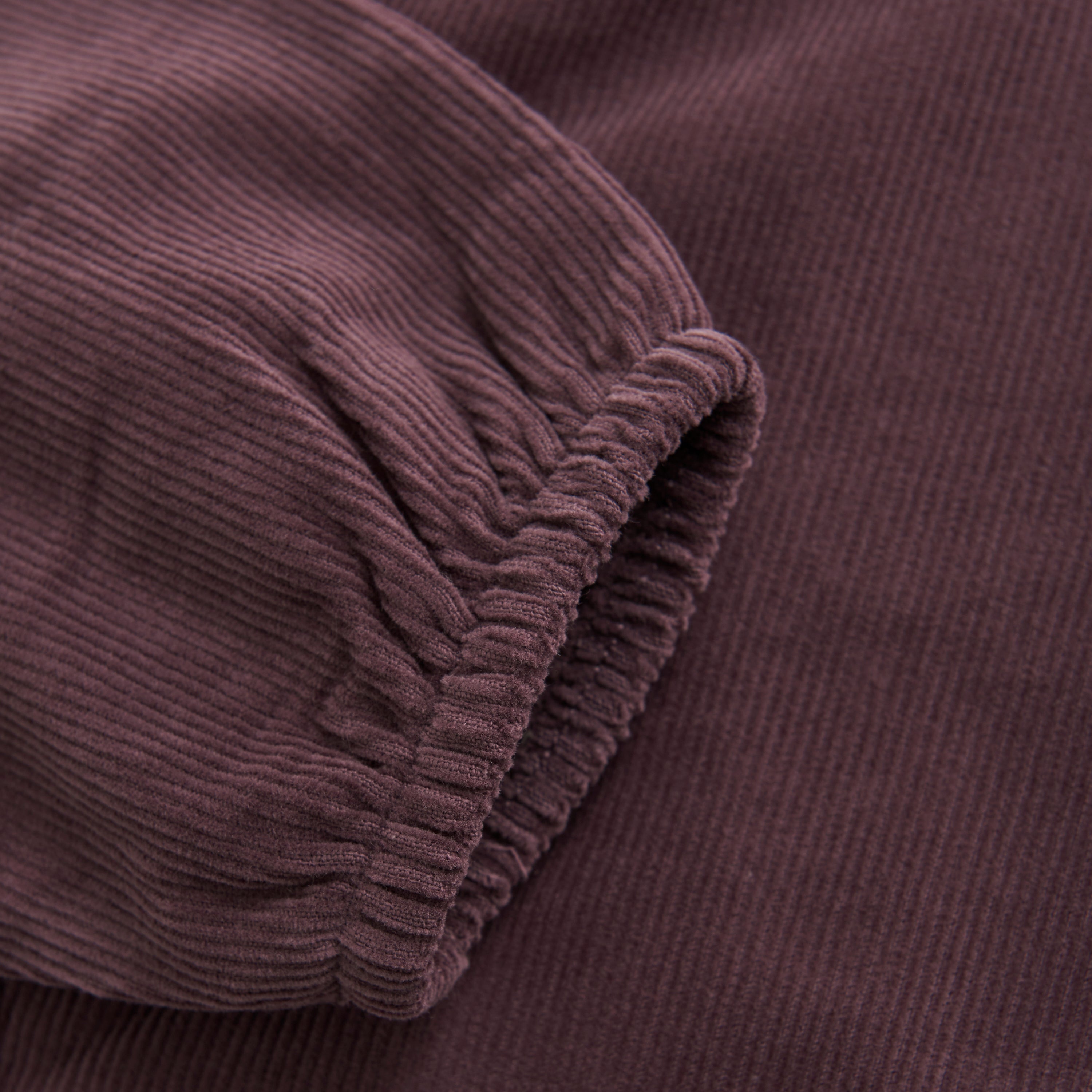 Nahaufnahme eines Ärmels aus kastanienbraunem Cordstoff mit elastischer Manschette. Die ausgeprägte Rippstruktur, die für Cord charakteristisch ist, spiegelt die Qualität der Hosen von Fixoni wider.