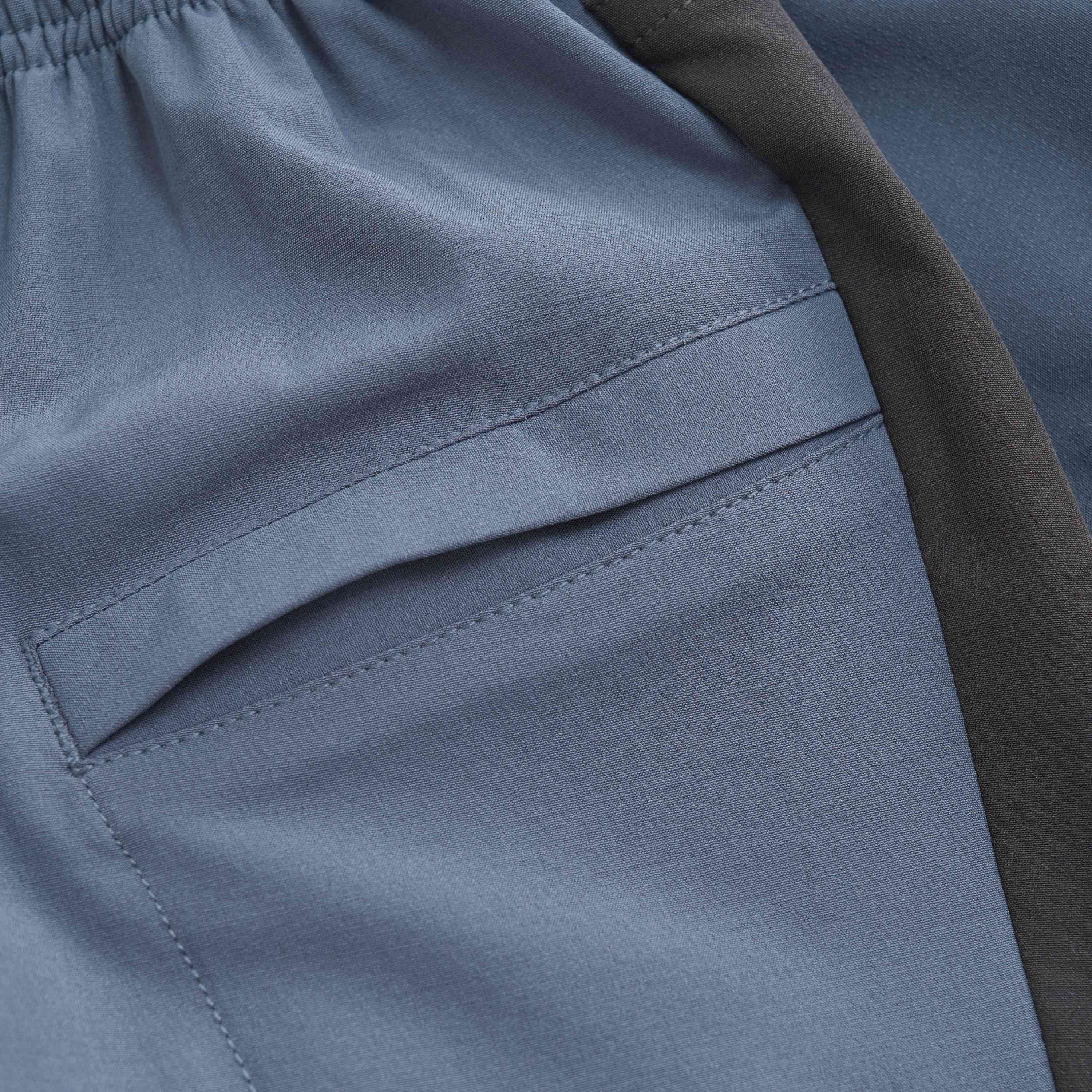 Nahaufnahme von Color Kids – Baby Pants Outdoor aus blauem und schwarzem Stoff. Das Bild konzentriert sich auf die linke Seitentasche und zeigt detaillierte Nähte und die Textur des Stoffes. Der Bund scheint elastisch zu sein und die Hose hat ein schlichtes, modernes Design, das von den Prinzipien fairer Kindermode inspiriert ist.