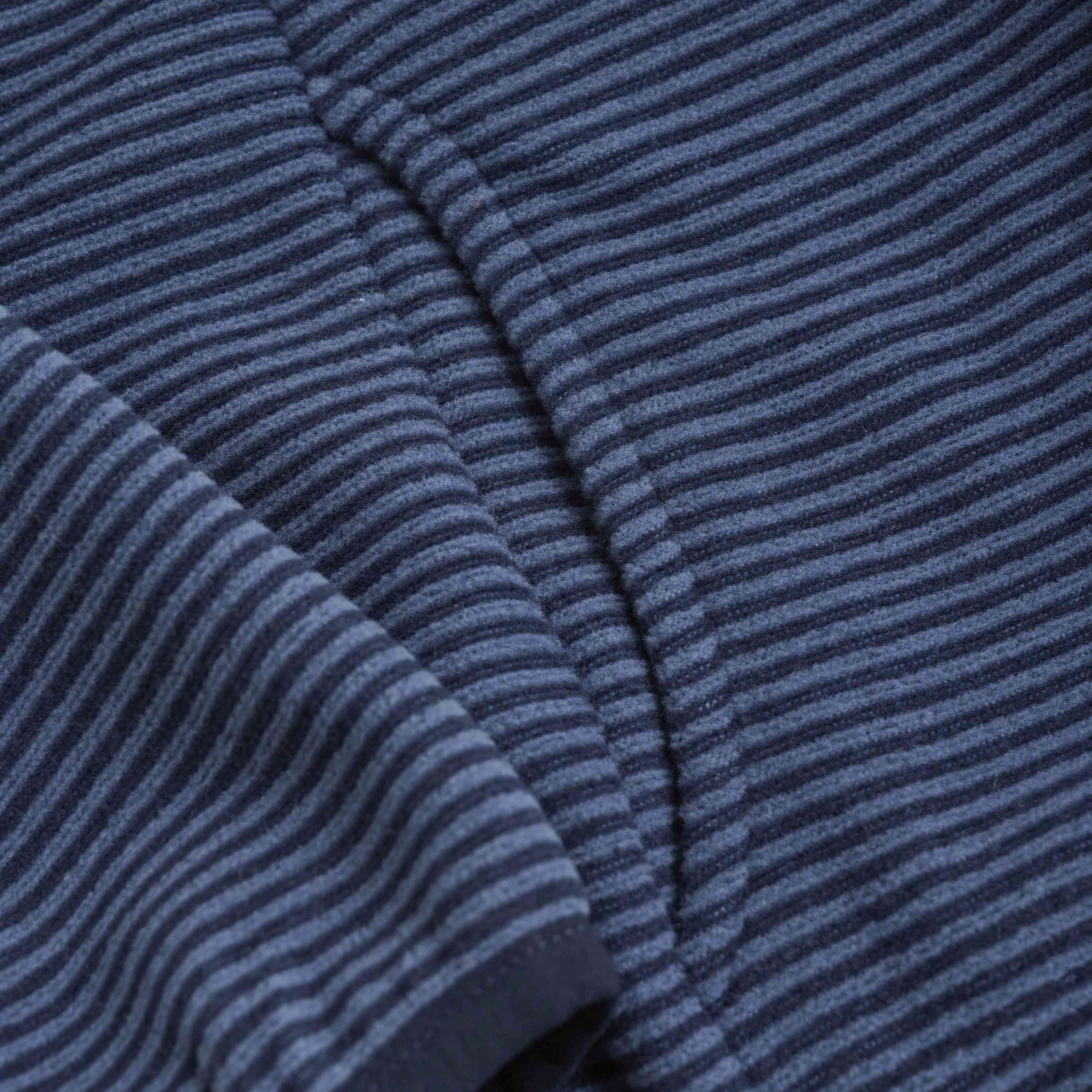 Nahaufnahme eines Kleidungsstücks mit einer Textur aus horizontalen blauen und schwarzen Streifen. Der Stoff wirkt weich und hat sichtbare Stiche, die auf eine Naht hinweisen. Die gleichmäßig gemusterten Streifen geben einen detaillierten Blick auf das Material frei, ideal für eine Color Kids - Fleecejacke von Color Kids.