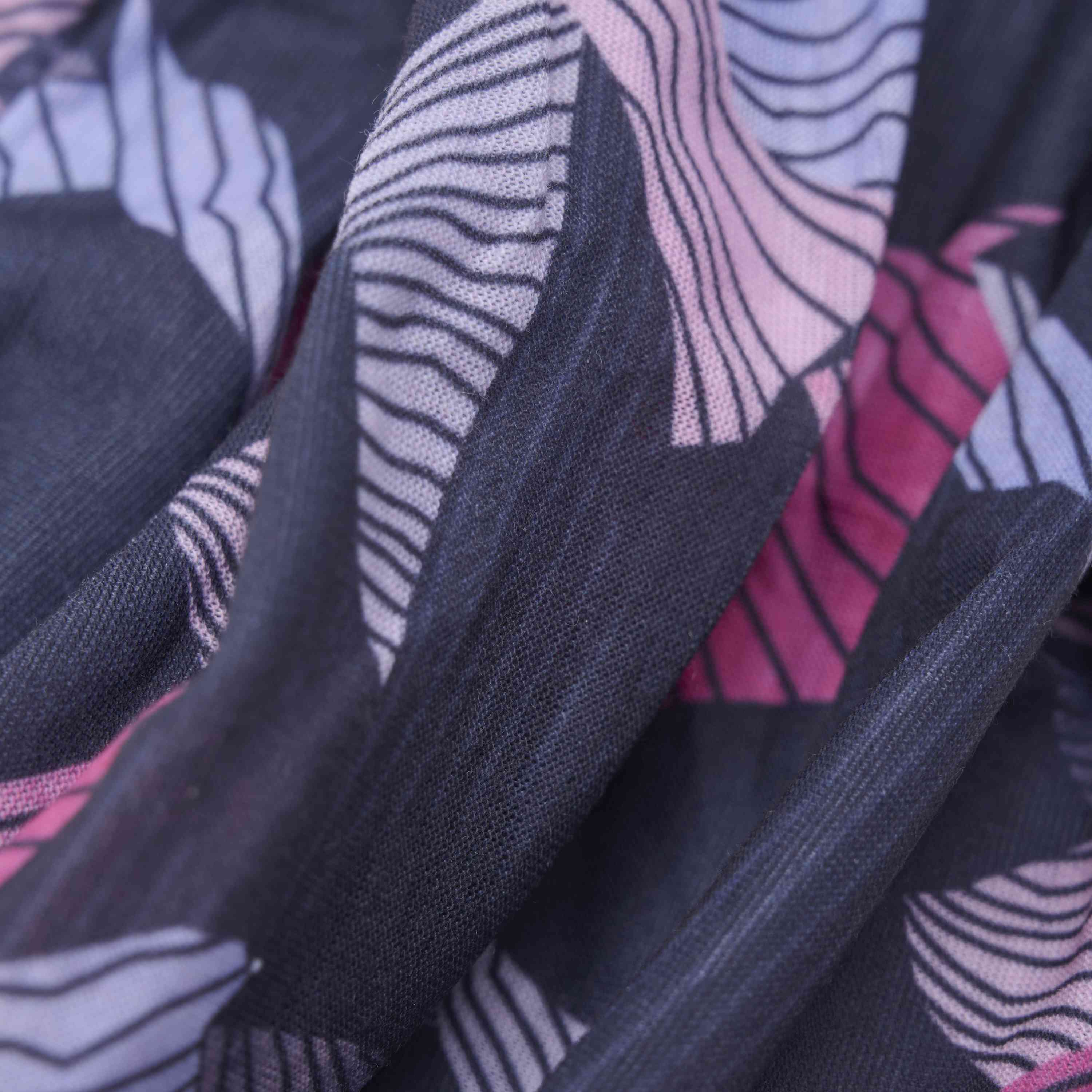 Nahaufnahme des *Color Kids - Neckwarmer - AOP* von Color Kids. Der Stoff zeigt abstrakte Formen in Rosa- und Blautönen auf dunklem Hintergrund. Die Textur wirkt weich und leicht plissiert.