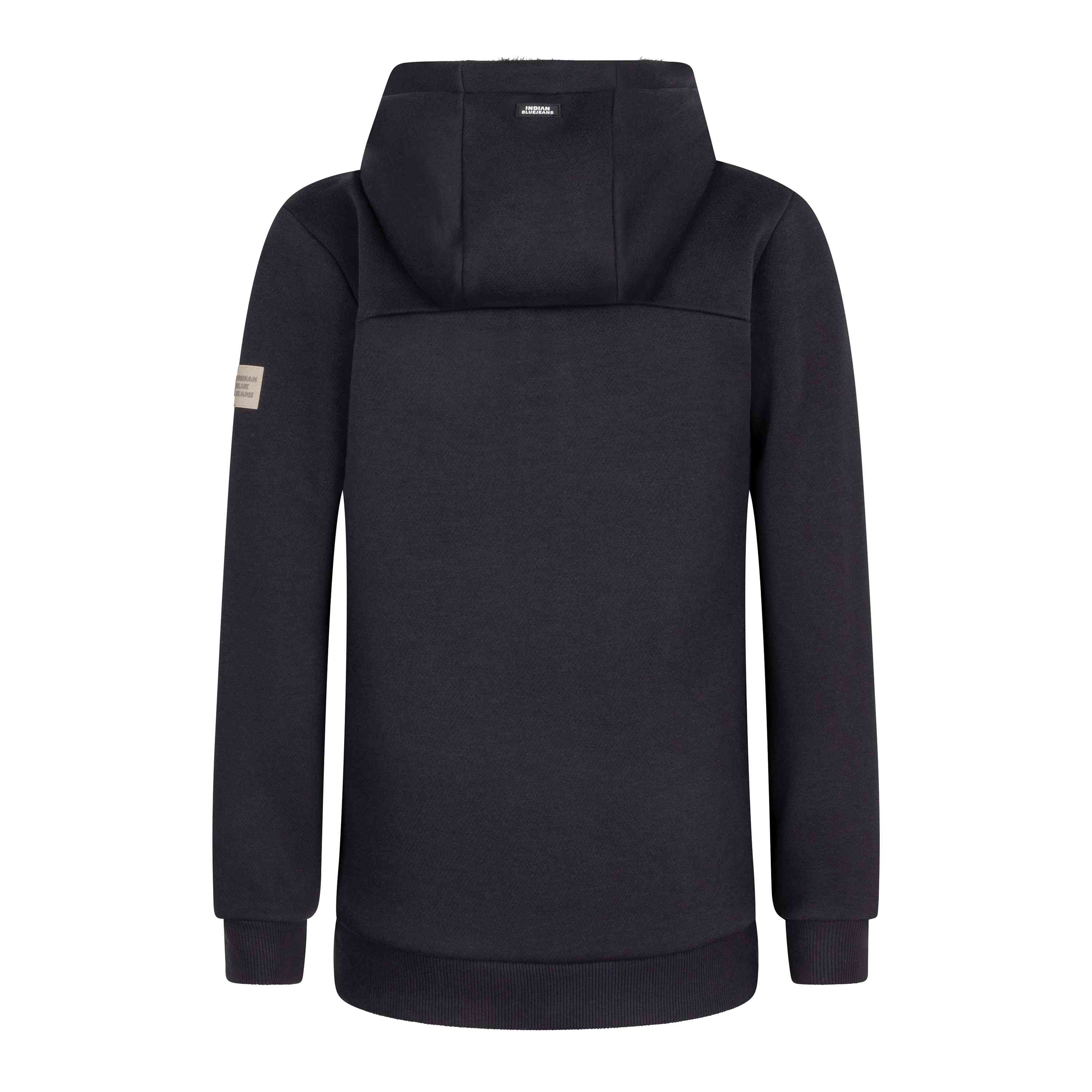 Ein Bild der Rückansicht des Indian Blue Jeans – Hooded Zipper Teddy Scuba in Schwarz, mit Kapuze und langen Ärmeln. Das Material scheint dick und warm zu sein. Oben in der Mitte neben der Kapuze befindet sich ein kleines Logo und am oberen rechten Ärmel ein kleiner Aufnäher. Die Bündchen und der Bund sind gerippt und sorgen in dieser Produktbeschreibung von Indian Blue Jeans sowohl für Stil als auch für Komfort.