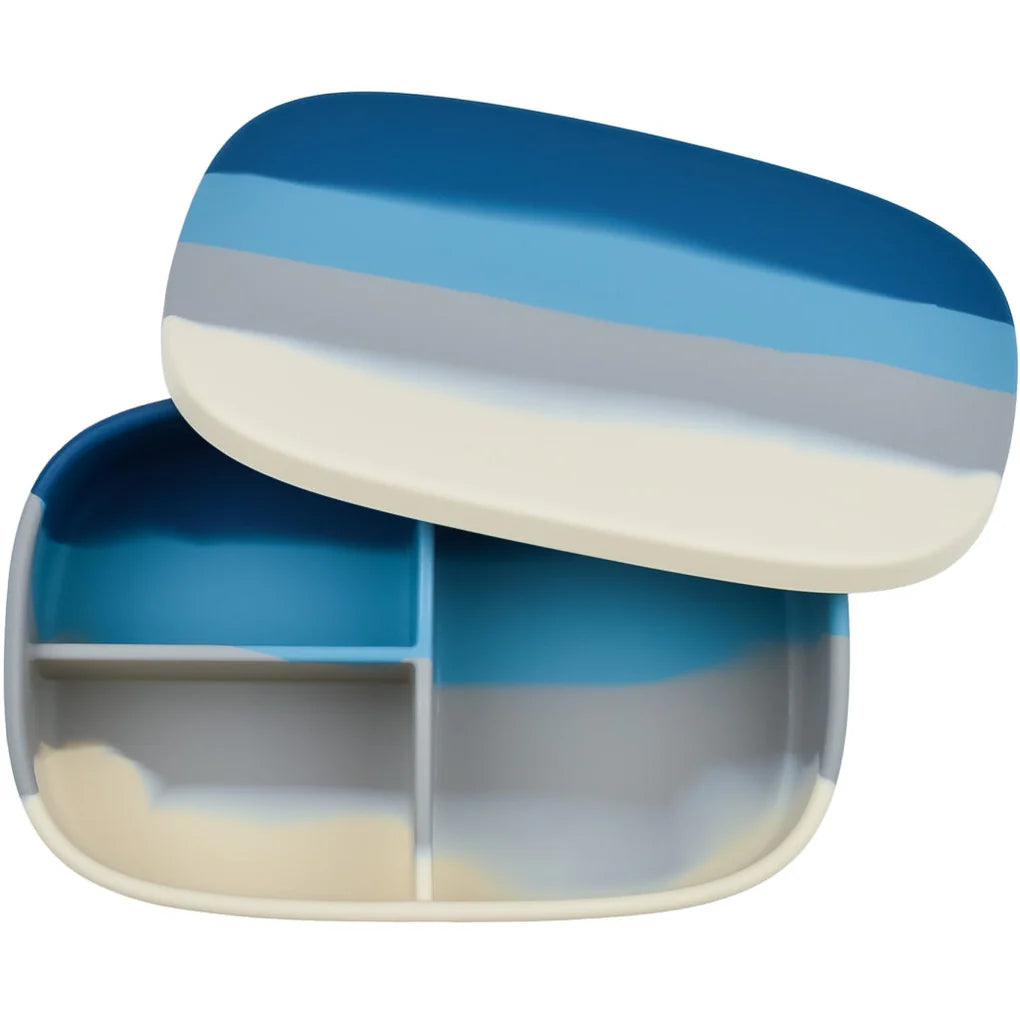 Eine rechteckige Bento-Box mit einem Deckel in Blau-, Weiß- und Beigetönen. Der Innenraum ist in drei Fächer unterteilt: ein großes und zwei kleinere, die dazu dienen, Lebensmittel getrennt aufzubewahren. Diese stilvolle Grech und Co. - Große Lunchbox aus Silikon sorgt dafür, dass das Mittagessen Ihres Kindes frisch und ordentlich aufbewahrt bleibt.