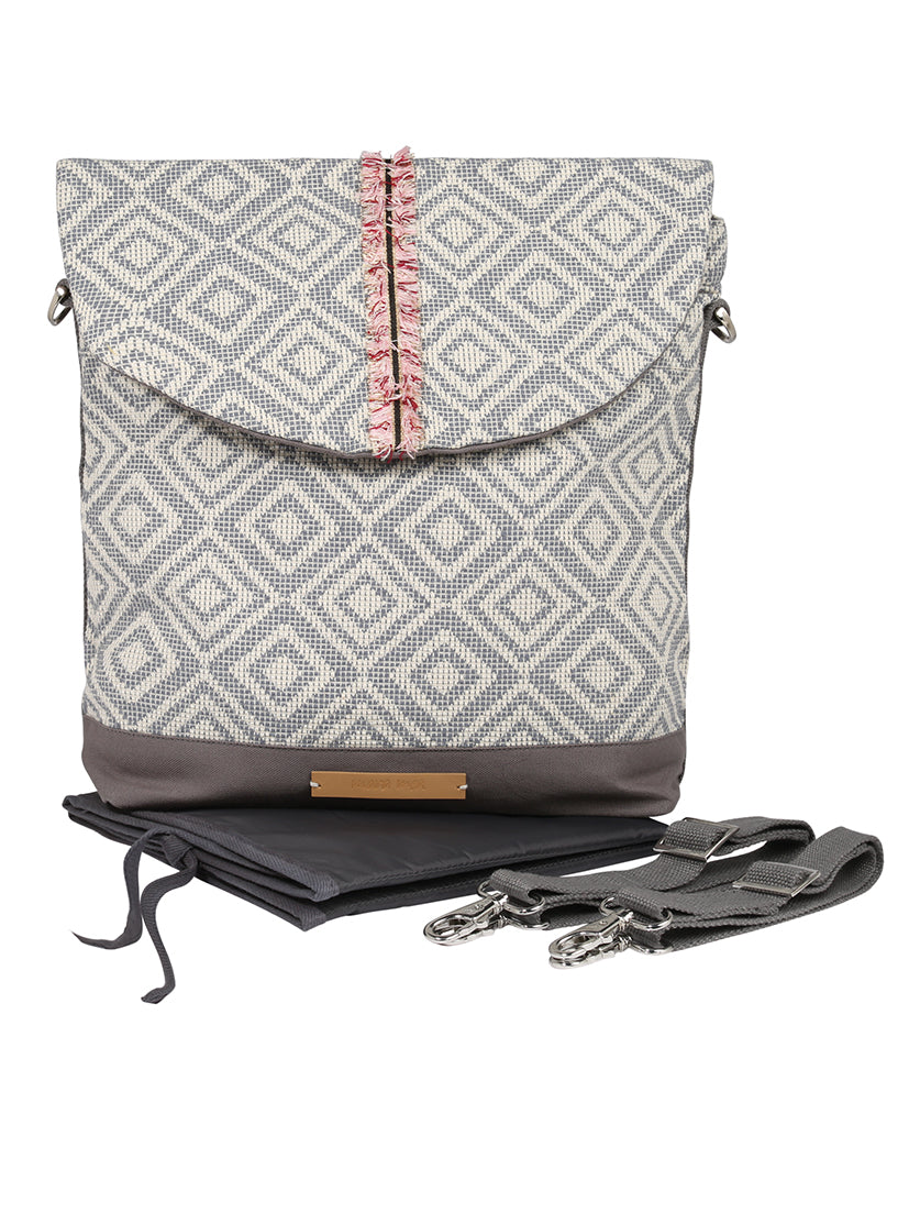 Ein stylischer Rucksack mit grau-weißem Rautenmuster und dekorativen rosa-grauen Fransen. Der Boden ist einheitlich grau mit einem eleganten braunen Etikett. Ausgestattet mit abnehmbaren Riemen enthält er außerdem eine gefaltete schwarze Wickelunterlage, die mit reflektierenden Aufklebern für zusätzliche Sicherheit verziert ist, vom Mara Mea mara mea - City Wickelrucksack - extra Romantik.