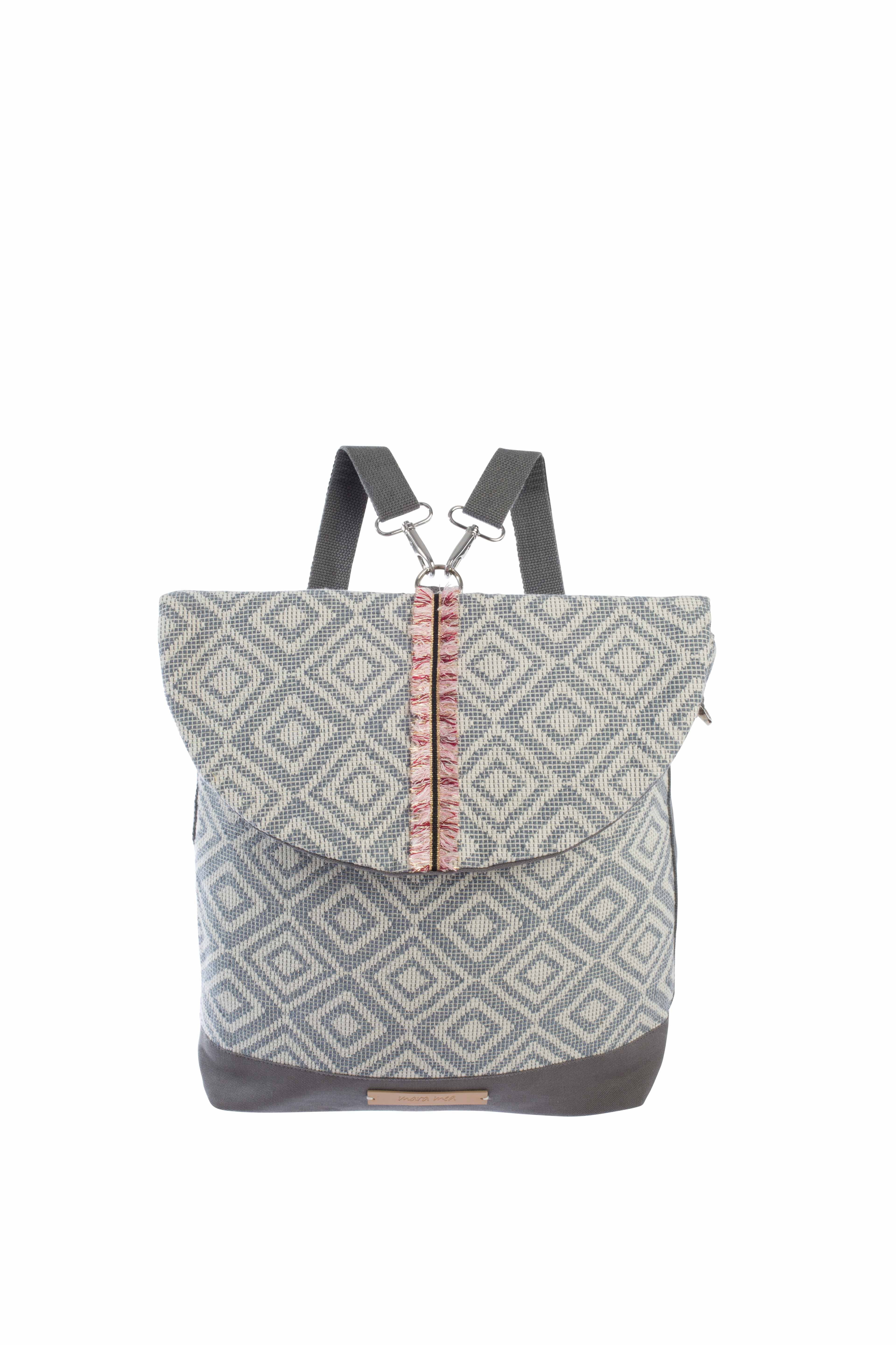 Der Mara Mea - City Wickelrucksack - extra romance ist ein stylischer, nachhaltiger Rucksack mit geometrischem Rautenmuster in Grau- und Weißtönen. Er hat eine Klappe mit rosa Akzent in der Mitte und schwarze Riemen. Der Boden der Tasche ist einfarbig grau, was ihn zu einer schicken und umweltfreundlichen Wahl aus Ihrem örtlichen Kinderartikelgeschäft macht.