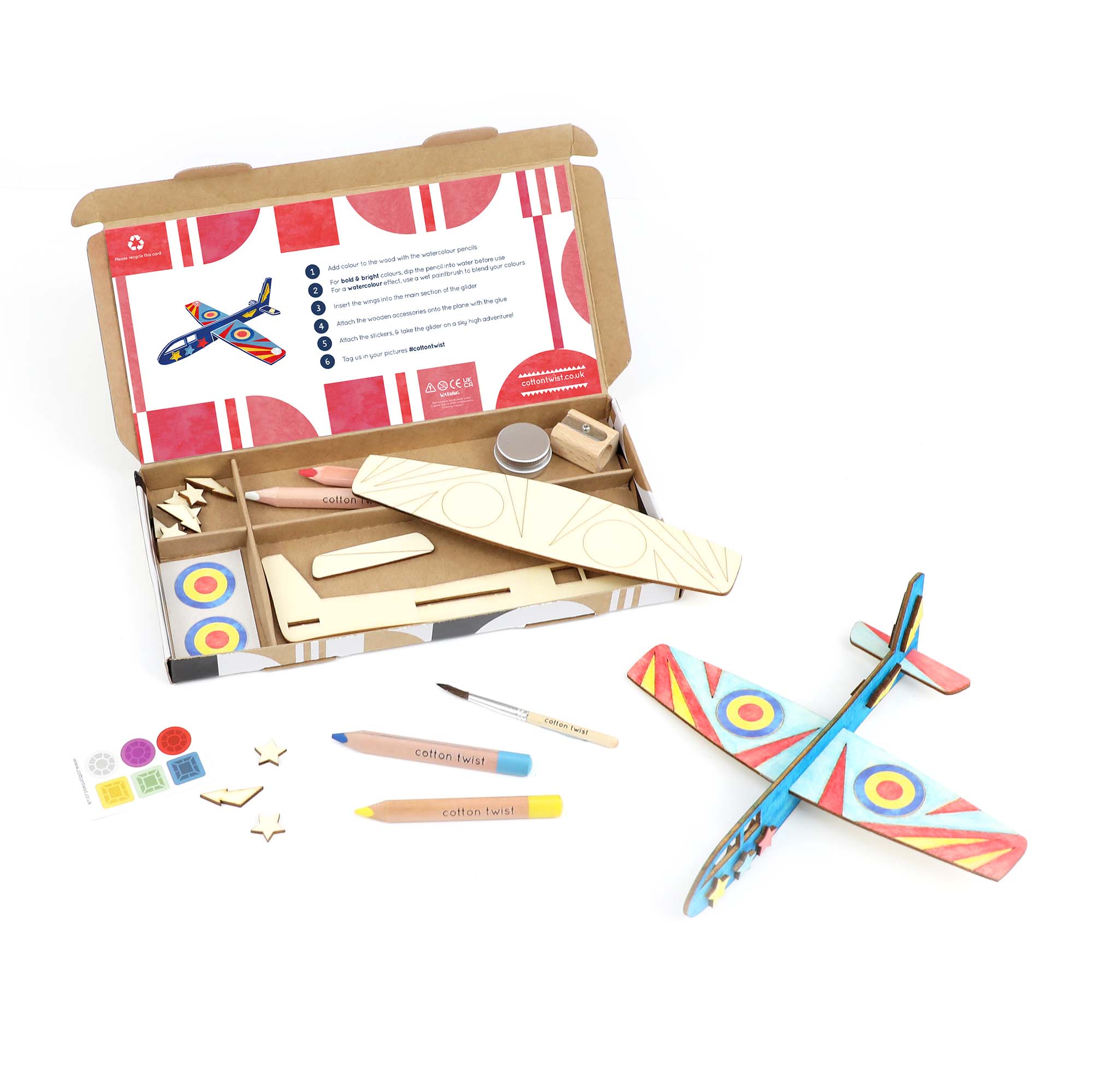 Es wird ein DIY-Bausatz für ein Flugzeug aus Holz gezeigt. Die Cotton Twist - DIY Flugzeug-Set Activity Box enthält bemalte Flugzeugteile aus Holz, Buntstifte, selbstklebende Schaumstoffaufkleber und eine ausführliche Anleitung. Das fertige Modellflugzeug, bemalt in leuchtenden Farben und Mustern, steht neben dem plastikfreien Kinderspielzeug-Bausatz von Cotton Twist.