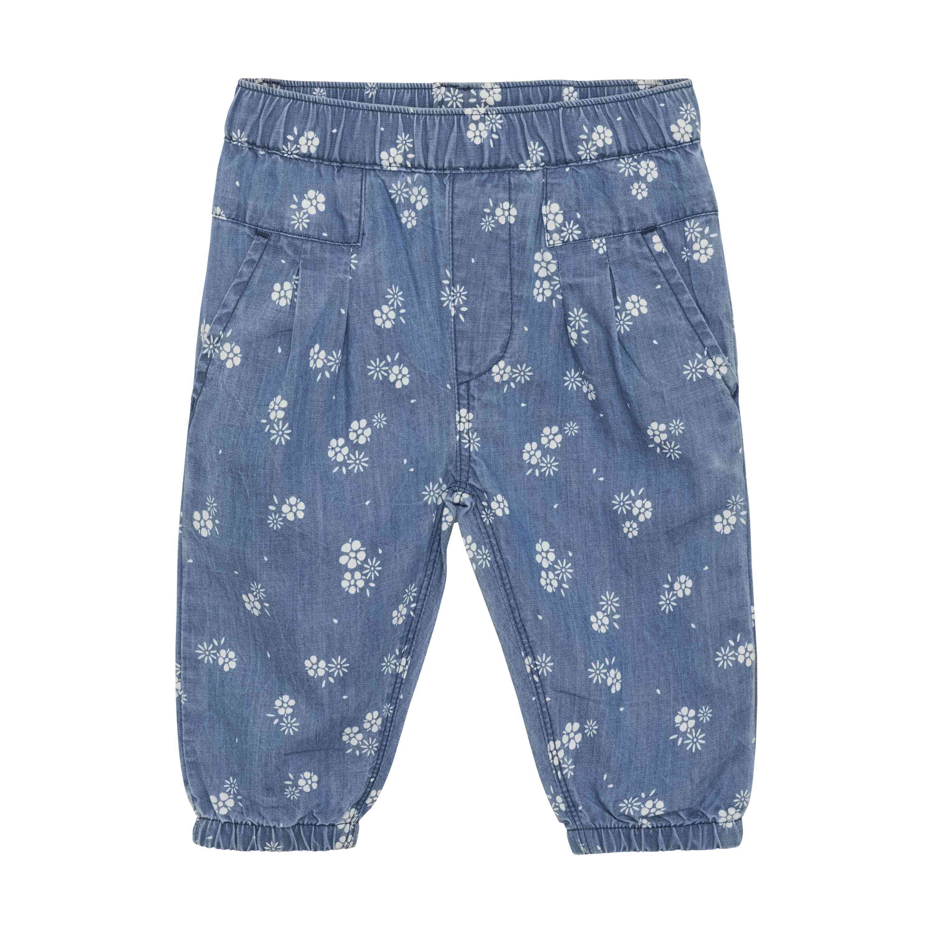 Minymo - Chambray-Hosen mit einem Muster aus kleinen weißen Blumen. Die Minymo-Hose aus GOTS-zertifiziertem Stoff hat einen elastischen Bund und Bündchen an den Knöcheln sowie Vordertaschen. Perfekt für alle, die faire Kindermode kaufen möchten.