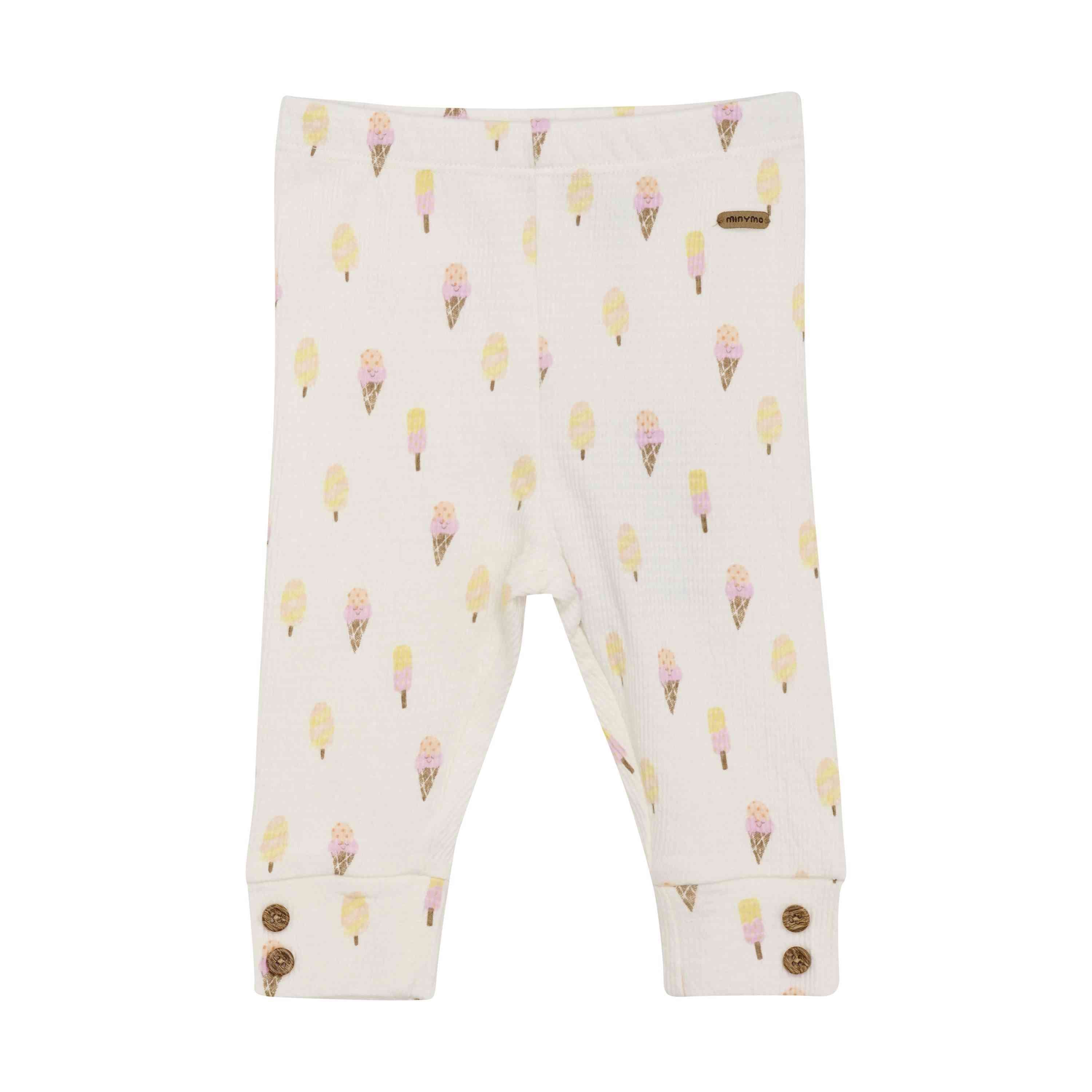 Weiße Baby-Leggings mit gelbem Eis am Stiel und Eistüten. Die Minymo - Leggings mit Allover-Print von Minymo im mädchenhaften Design haben einen gerippten Bund, hochgekrempelte Bündchen mit braunen Knöpfen und ein kleines Stoffetikett am Bund.