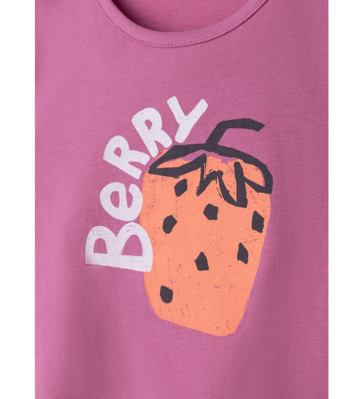 Das Sanetta T-Shirt von Sanetta besteht aus einem rosa Stoff, der mit einer großen, stilisierten orangefarbenen Erdbeere mit schwarzen Samen und Blättern verziert ist. Das Wort „BERRY“ ist in Weiß gedruckt und wölbt sich um die obere linke Seite der Erdbeere. Dieses charmante Frontdruckdesign ist aus hochelastischer Bio-Baumwolle gefertigt und sorgt für Komfort und Nachhaltigkeit.