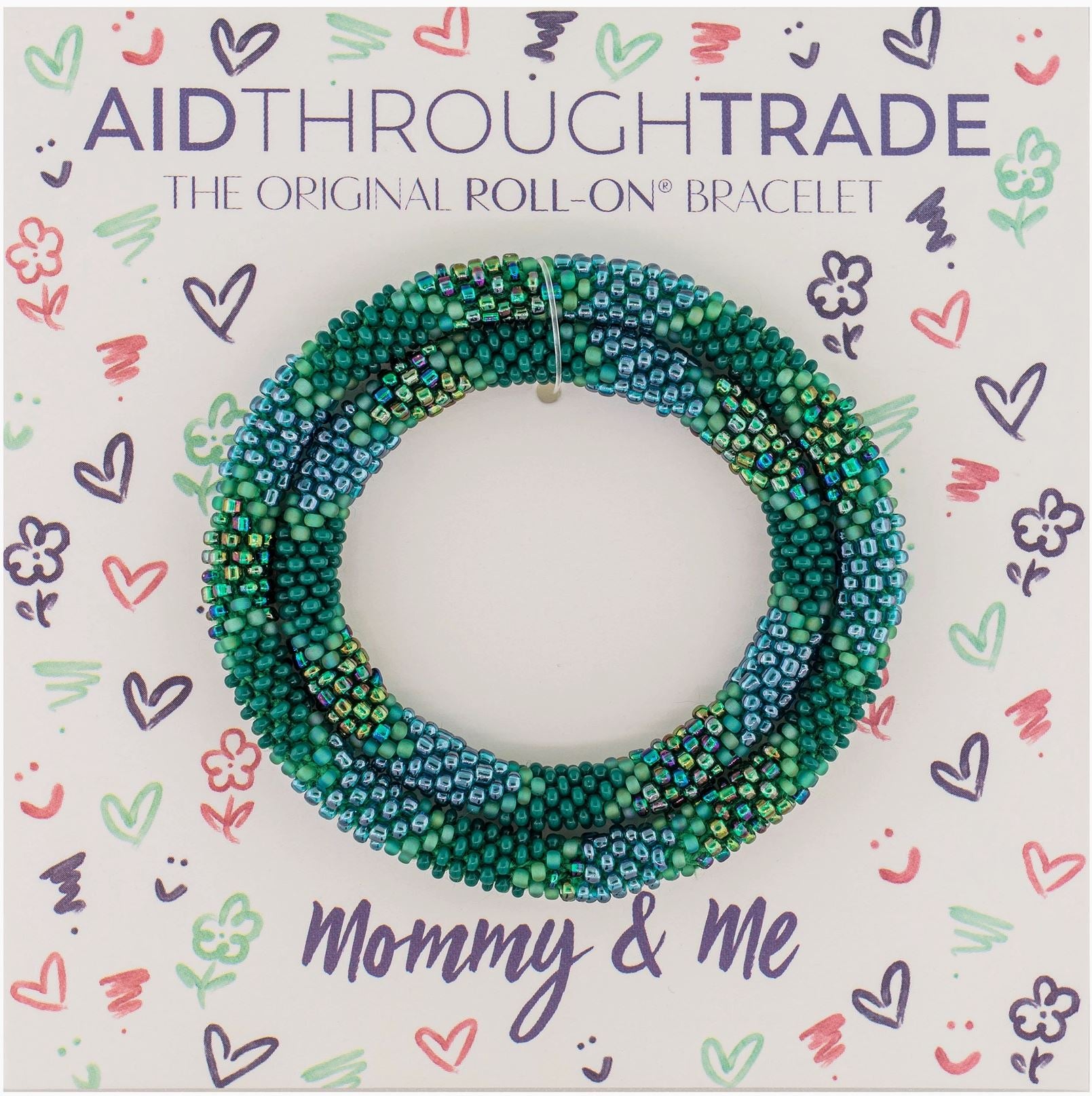 Ein Set mit Perlen von Aid Through Trade – Armbänder Mommy & Me in Blau- und Grüntönen wird auf einer Karte mit bunten Kritzeleien von Herzen, Sternen und Smileys präsentiert. Auf der Karte steht „Aid Through Trade – Das Original-Roll-On-Armband Mommy & Me“, stolz gefertigt von Frauenhandwerkerinnen in Nepal.