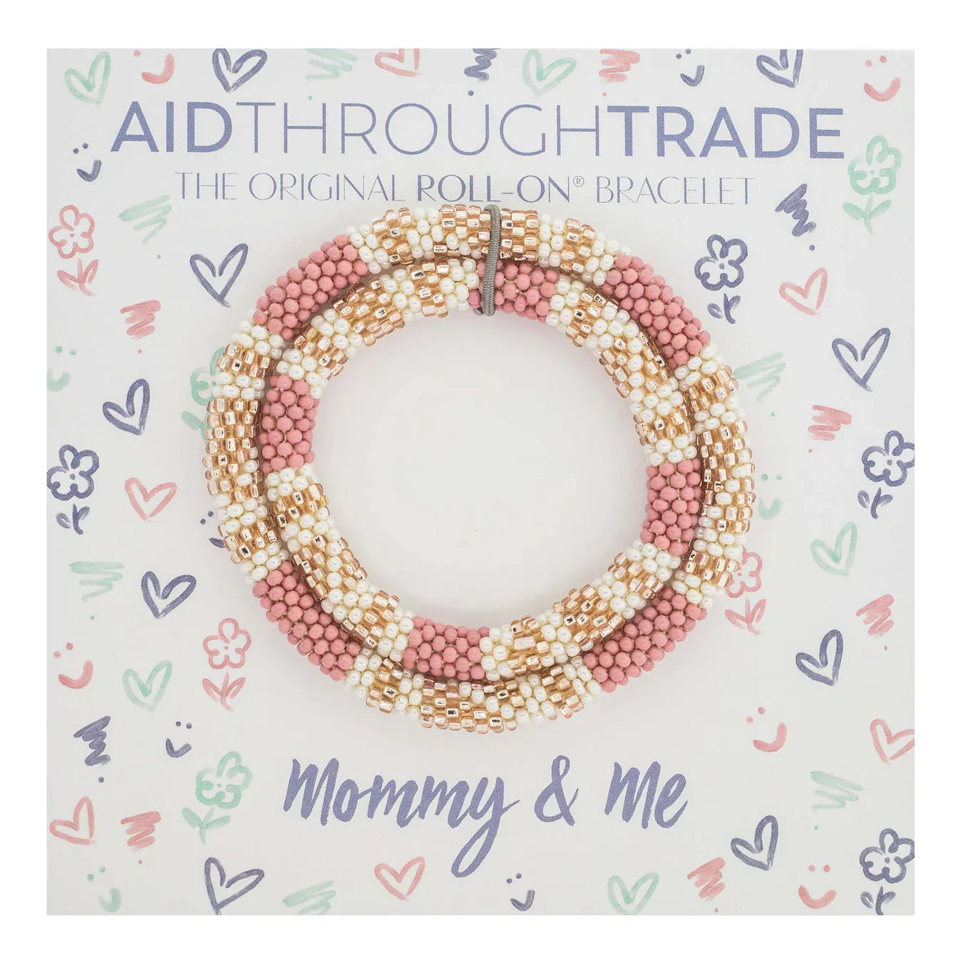 Ein Set aus rosa und weißen Perlenarmbändern von Aid Through Trade, präsentiert auf einer Karte, die mit verspielten Kritzeleien von Herzen, Sternen und Blumen verziert ist. Auf der Karte steht „Aid Through Trade – Armbänder Mommy & Me The Original Roll-On® Bracelets“, hervorgehoben in buntem Text und mit hochwertigen Glasperlen.