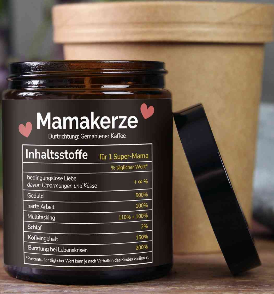 Ein braunes Glas mit der Aufschrift „mysoy – Mamakerze“ und einem Duft nach gemahlenem Kaffee steht offen vor einem hellbraunen zylindrischen Behälter. Das Glas, perfekt für eine Einrichtung für ein junges Kinderzimmer, enthält eine humorvolle Zutatenliste für eine „Super-Mama“, darunter Liebe, Geduld, harte Arbeit, Multitasking und Schlaf.