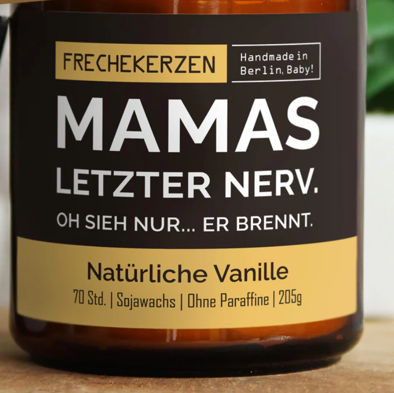 Eine Nahaufnahme eines braunen Kerzenglases mit einem schwarz-weißen Etikett, perfekt zur Dekoration eines Kinderzimmers. Auf dem Etikett steht „FRECHEKERZEN MAMAS LETZTER NERV. OH SIEH NUR… ER BRENNT.“ und „Handmade in Berlin, Baby! Natürliche Vanille, 70 Std., Sojawachs, Ohne Paraffine, mysoy – Mamakerze letzter Nerv von mysoy.