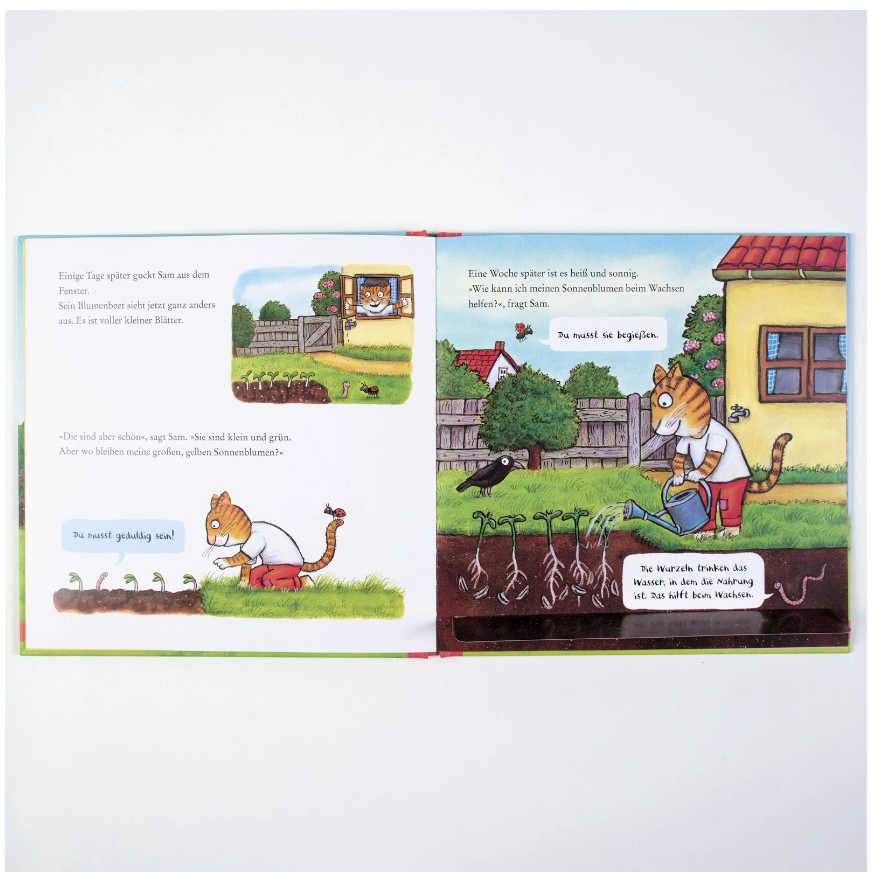 Ein aufgeschlagenes Kinderbuch mit illustrierten Zeichnungen zeigt eine Tigerfigur, die Pflanzen in einem Garten gießt. Die Szene umfasst ein Haus und einen Zaun im Hintergrund. Es gibt einen erzählenden Text in einer Mischung aus deutschen und übersetzten Teilen, der verschiedene Gartenarbeiten beschreibt, in denen überall Sonnenblumen verstreut sind. Der Produktname lautet *Sam pflanzt Sonnenblumen* von nila kids.