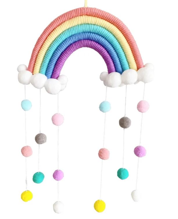 Ein Artilady - Regenbogen Wanddeko Makramee aus Garn, perfekt für ein Babyzimmer-Theme. Es besteht aus Bändern in Rosa, Orange, Gelb, Grün, Blau und Lila. An jedem Ende sind weiße Pomponwolken mit herabhängenden Schnüren befestigt, die mit kleinen, bunten Filzbällen geschmückt sind.